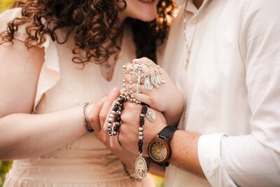 an engaged couple holding Catholic rosary beads