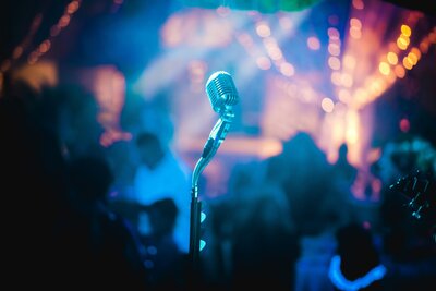 Solo silver microphone at a bar with blurred background in blues and light pinks. 
