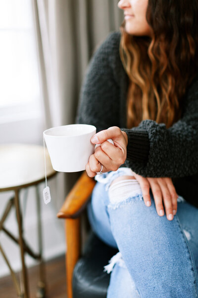 Woman holding a white mug with tea