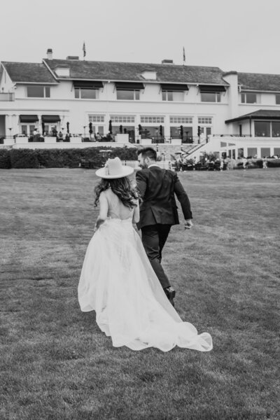 black and white image bride and groom holding hands walking on 18th hole at pebble beach