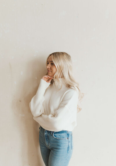 Colorado Brand Studio Photoshoot for Jadyn Alexa Films. Jadyn Anderson wearing a cream sweater and blue jeans standing and looking to the side
