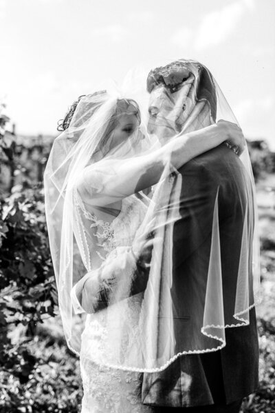 Black and white portrait of bride and groom under veil