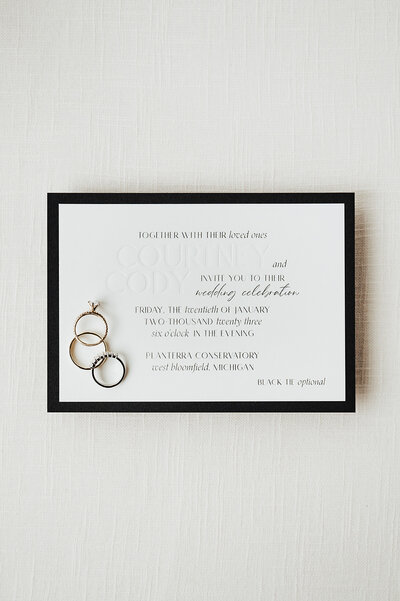 custom wedding stationery and design black and white debossed invitation suite with rings against a white background