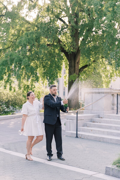 Couple spraying champagne at PA State Capitol during engagement session