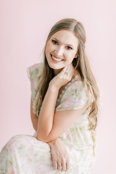 A Mississippi wedding photographer smiles big in front of a pink wall.