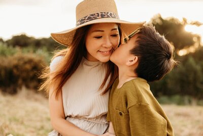 A little boy kissing his mum on the cheek during their family photoshoot with auckland photographer michelle kelly
