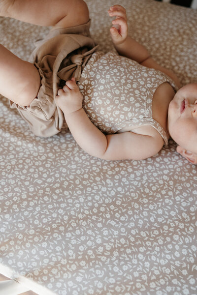 Baby wearing a cozy outfit, lying on a soft blanket with natural lighting.
