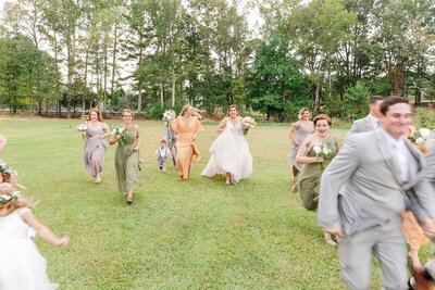 wedding party running through a field
