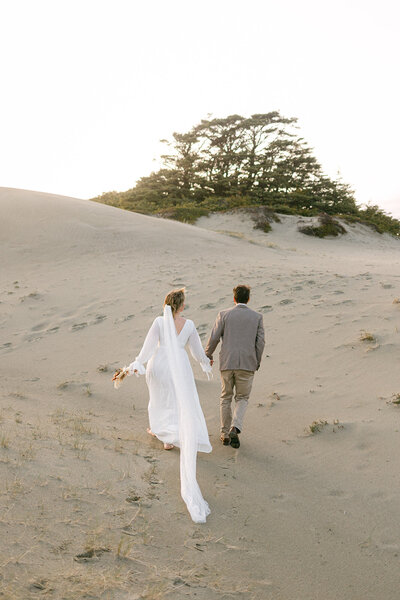 an eloping couple walks down the sand dunes on Wick Beach  near Tofino, BC