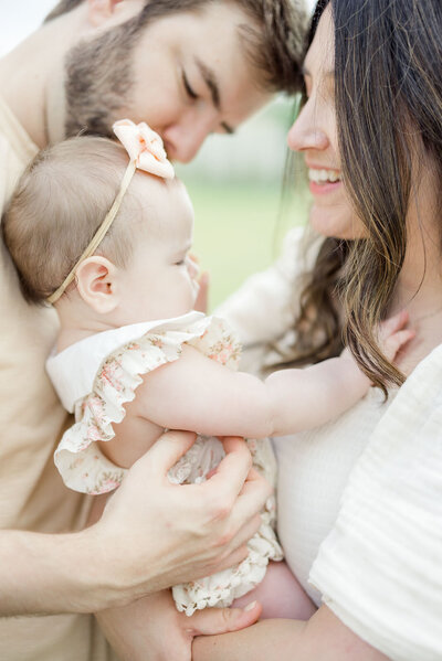 Mom and dad looking at baby held between them for portrait photographer session in Tampa