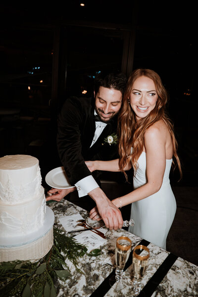 Bride and groom laughing as they cut their wedding cake in Breckenridge, Colorado.