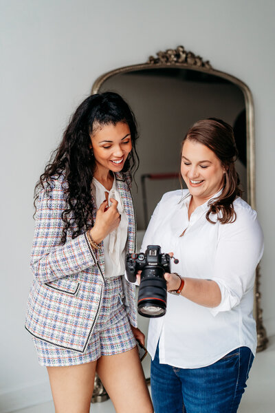 Two women looking at a camera during a photoshoot.