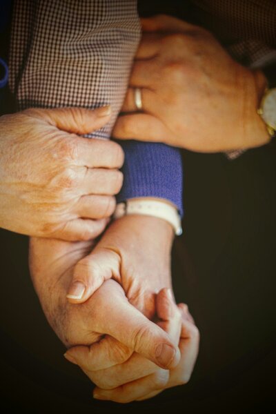 Close up image of older married couple holding hands