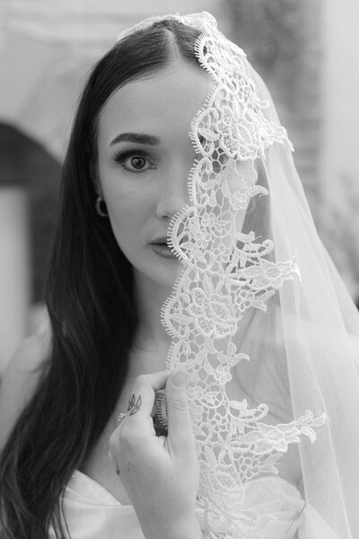 Fashion forward editorial black and white portrait of a bride getting ready in her vintage lace veil 