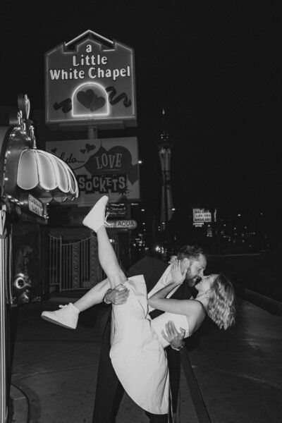 ust-married couple sharing a kiss under the pink neon sign at the Little White Wedding Chapel in Las Vegas