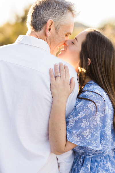 Man and woman nuzzling with the focus on the engagement ring