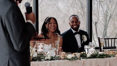 Bride and groom  sit at reception together and smile