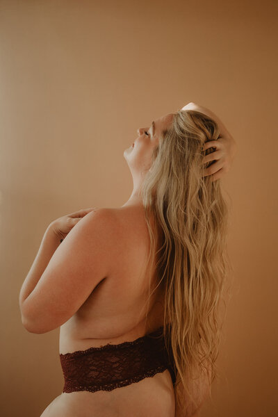 A person leaning back with one hand in their hair and the other on their chest 