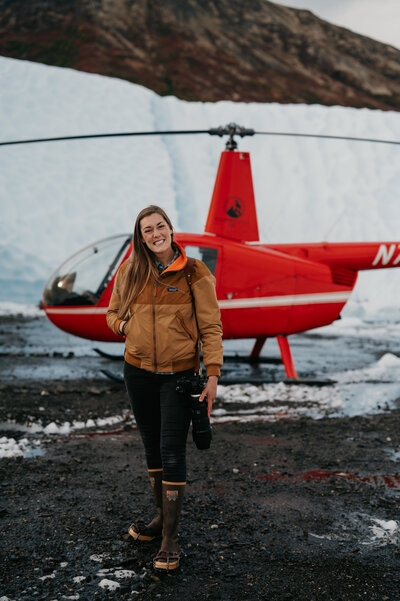 woman standing by helicopter on glacier