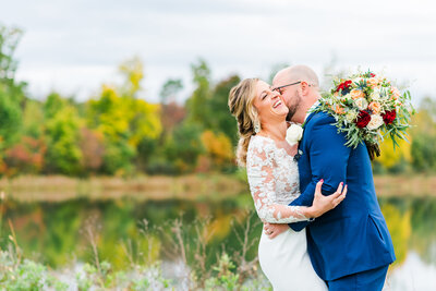 bride and groom hugging close while groom kisses her ear