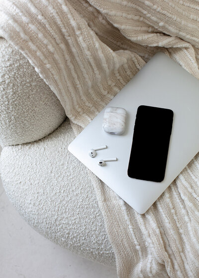 iPhone, airpods, and laptop laying on the bed