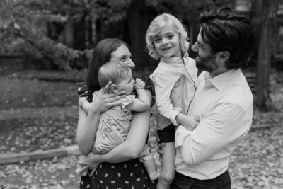 Black and white image of a mother and father holding their children outside their home