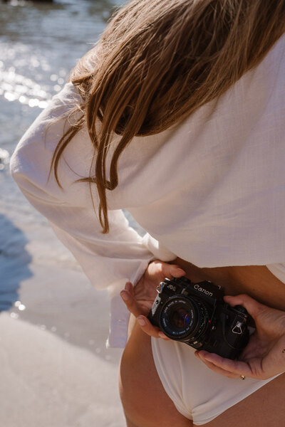 An Ibiza photographer is holding an analog camera behind her back.