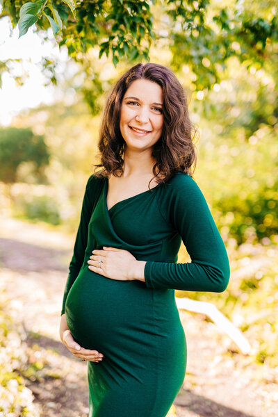 Mother and father cradle baby bump by a lake