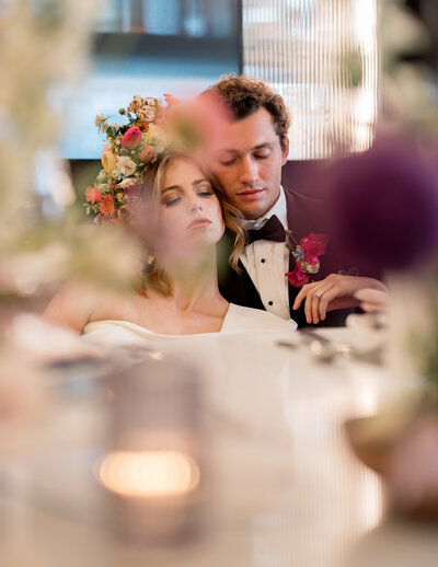 Bride and groom sharing an intimate moment, surrounded by warm lighting and floral decorations.