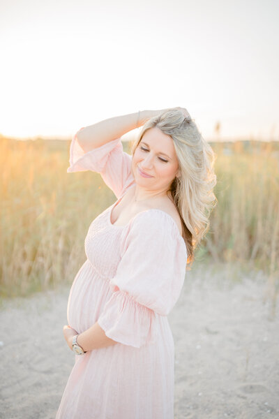Pregnant mom standing in a field during golden hour, wearing a beautiful flowy dress, capturing a peaceful and radiant moment