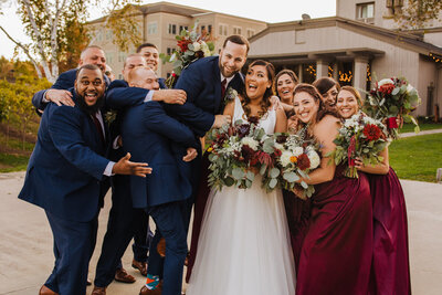 bride and groom being hugged by enthusiastic wedding party