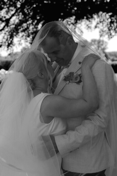 Intimate kiss between newlyweds in the Salt House garden with floral backdrops