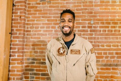 Black army veteran smiling in front of brick wall