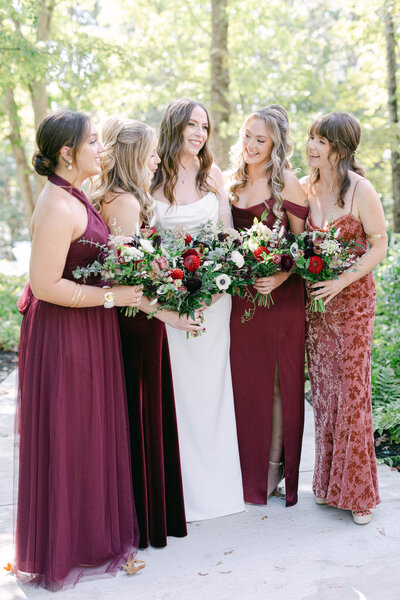 bride with bridesmaids dressed in shades of red laughing  knoxville tennessee wedding photographer