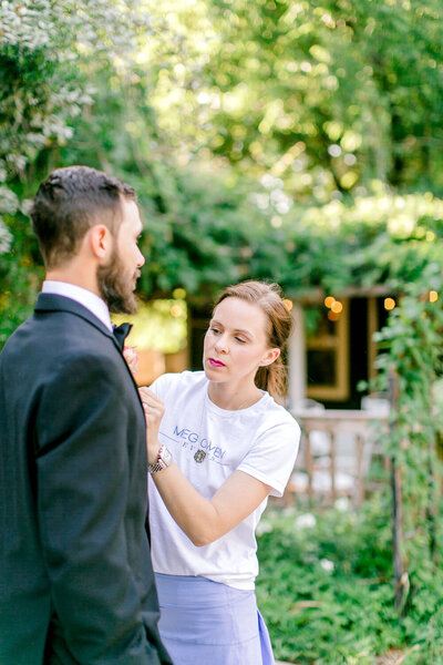 Meg pinning a boutonniere on a groom