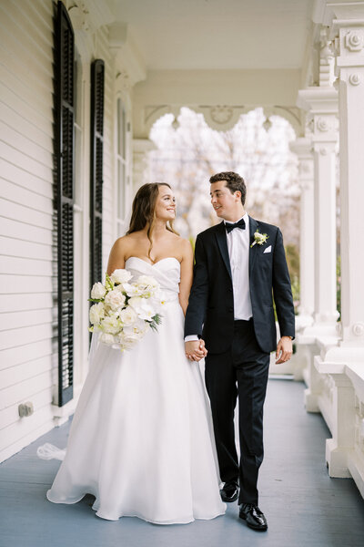 Bride and groom walking under the porch at Merrimon Wynne wedding venue