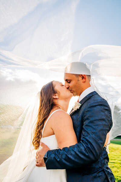 Denver Wedding Photographer captures bride and groom kissing under veil