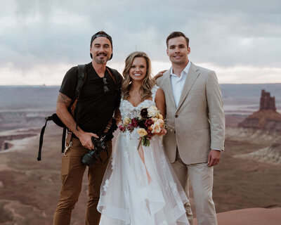 bride and groom standing with their wedding photographer in the desert