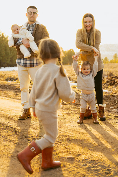 Mom is looking at the camera  while holding her son in a golden field