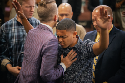 Evangelist Jonathan Shuttlesworth prays for a young man at Crossroads Community Church in Fitchburg MA