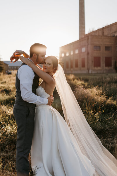 new bride and groom embracing in sunset