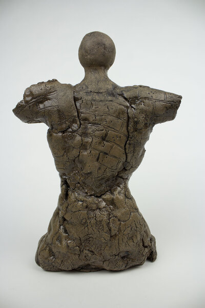 A ceramic bust of a feminine body with various cracks and brick textures