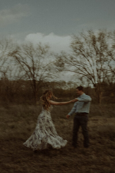 Blurred photo of a husband spinning his wife in a field.