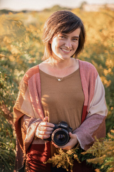 Stephanie, Denver wedding photographer smiles at the camera in a field of golden rod.