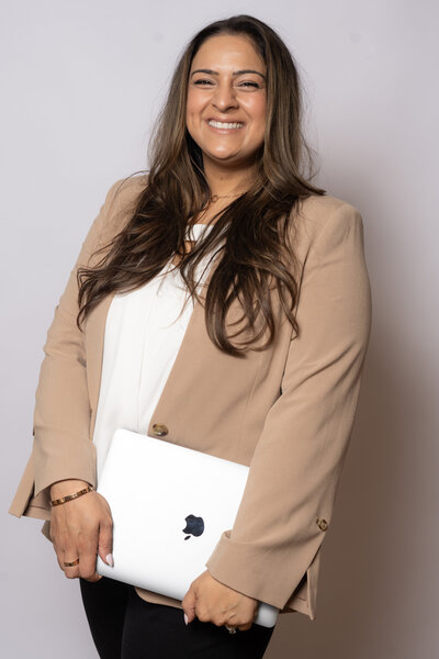 The  dedicated business operations consultant, dressed in a sophisticated beige blazer and black pants, equipped with her laptop computer to streamline your business processes and drive growth.