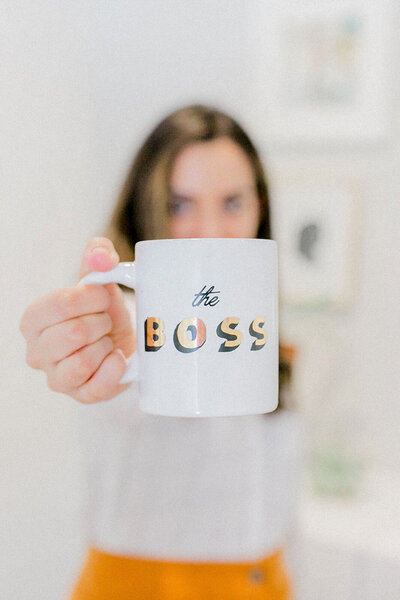 woman holding up a mug reading "the BOSS"