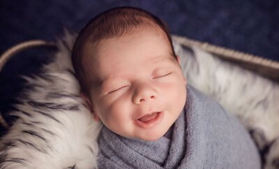 A sleeping baby in a basket, gently swaddled in a soft, colorful blanket.