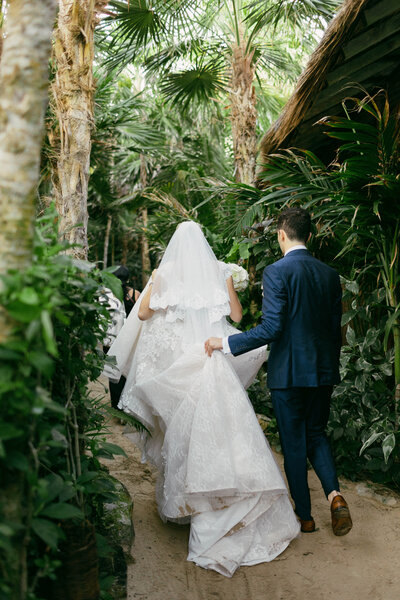 Bride and groom walking in the jungle path, groom assisting bride with her dress