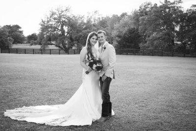 Austin-based wedding photographer captures a stunning black and white photo of a bride and groom standing in a field.
