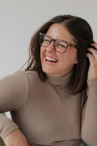 A person smiling and tucking hair behind her ear 